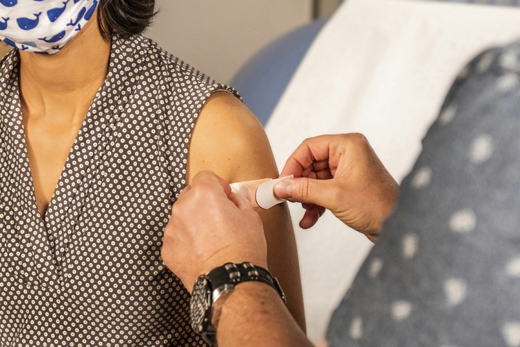 Woman receiving a band aid from a doctor after a vaccination