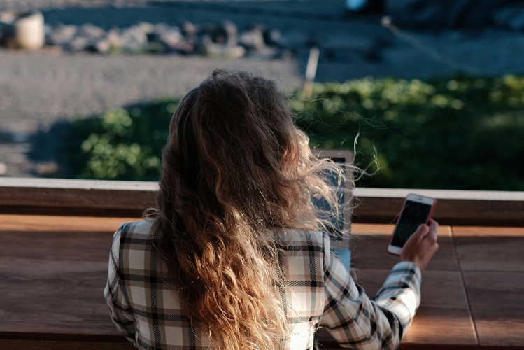 Woman sitting on a porch using a laptop and smartphone