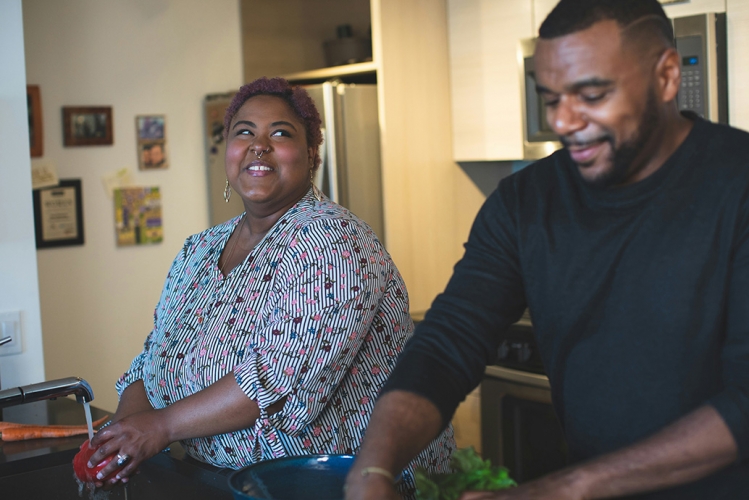 Woman and man couple washing vegetables and talking